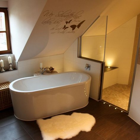 Das Badezimmer zeigt eine stilvolle Badewanne, große Fenster und eine Dusche, die durch eine Glaswand abgetrennt ist.