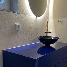 Der stilvolle Waschbereich zeigt eine glänzende blaue Oberfläche und eine schlichte schwarze Schüssel, umgeben von sanftem Licht.