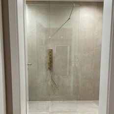 Ein eleganter Duschraum mit einer transparenten Wand und einer goldenen Duschsteuerung, die ein Gefühl von Luxus vermittelt.