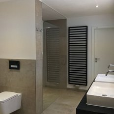 Das Badezimmer zeigt eine stilvolle Einrichtung mit hellen Fliesen, einem WC und einem großen Spiegel über den Waschbecken.