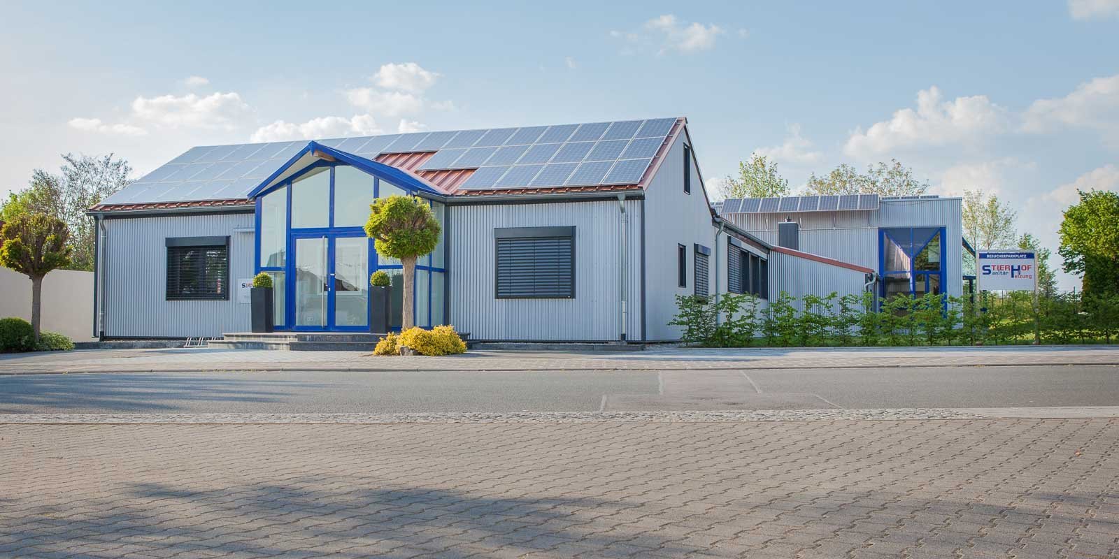 Das Gebäude zeigt eine Kombination aus modernen architektonischen Elementen und umweltfreundlichen Solarpanelen auf dem Dach.