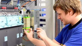 Ein Elektroniker der an einer Klemmverbindung schraubt