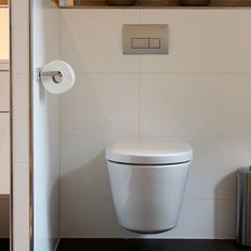 Die schlichte, stilvolle Toilette steht in einem hellen Raum mit weißen Fliesen und einem minimalistischen Design.