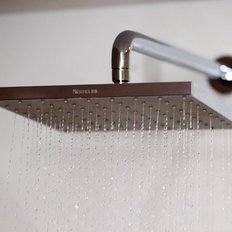 Der elegante Duschkopf aus Edelstahl sprüht feine Wasserstrahlen in einem hellen Badezimmer.